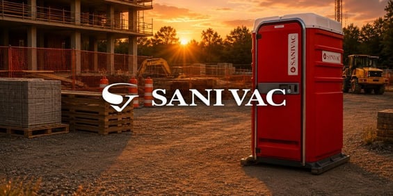 Toilette portable Sanivac rouge sur un chantier de construction au coucher du soleil.